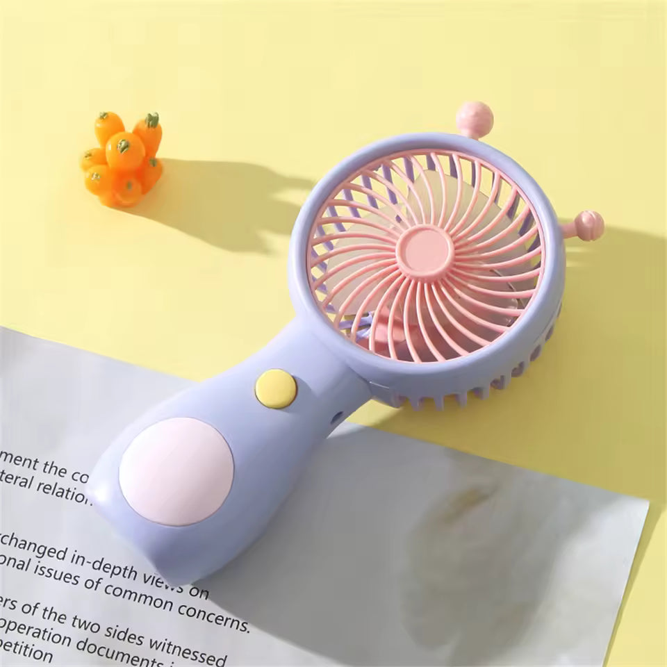 Portable mini fan USB rechargeable handheld fan in pastel colors on yellow surface