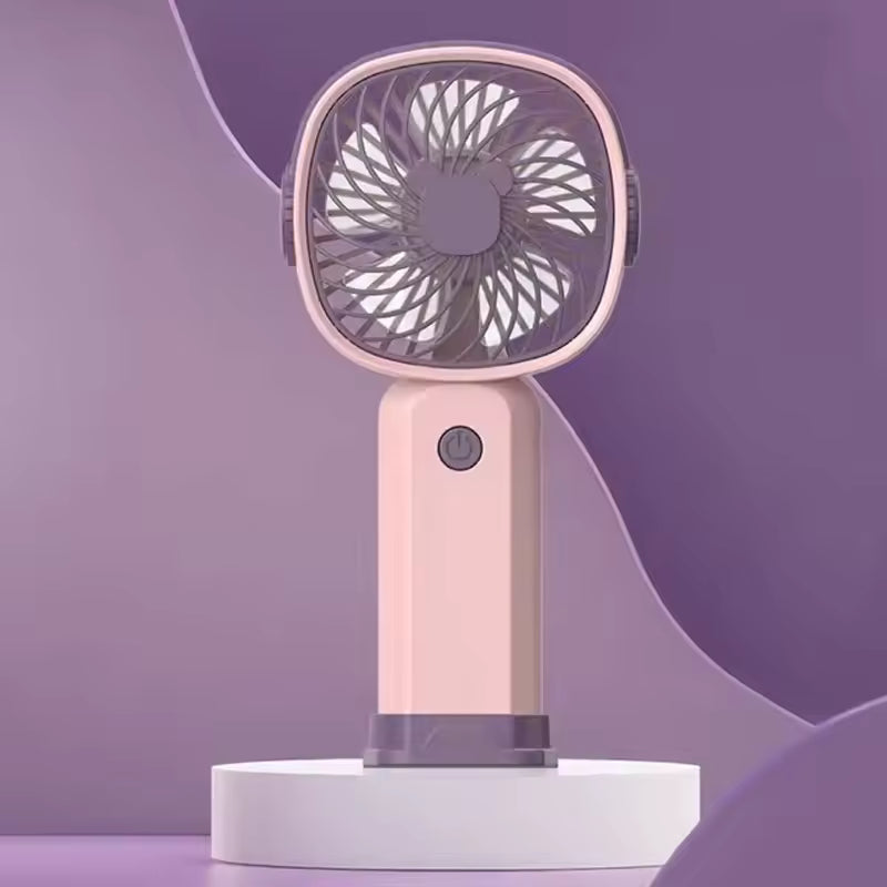 Pink portable mini fan USB rechargeable with compact design and power button on purple background