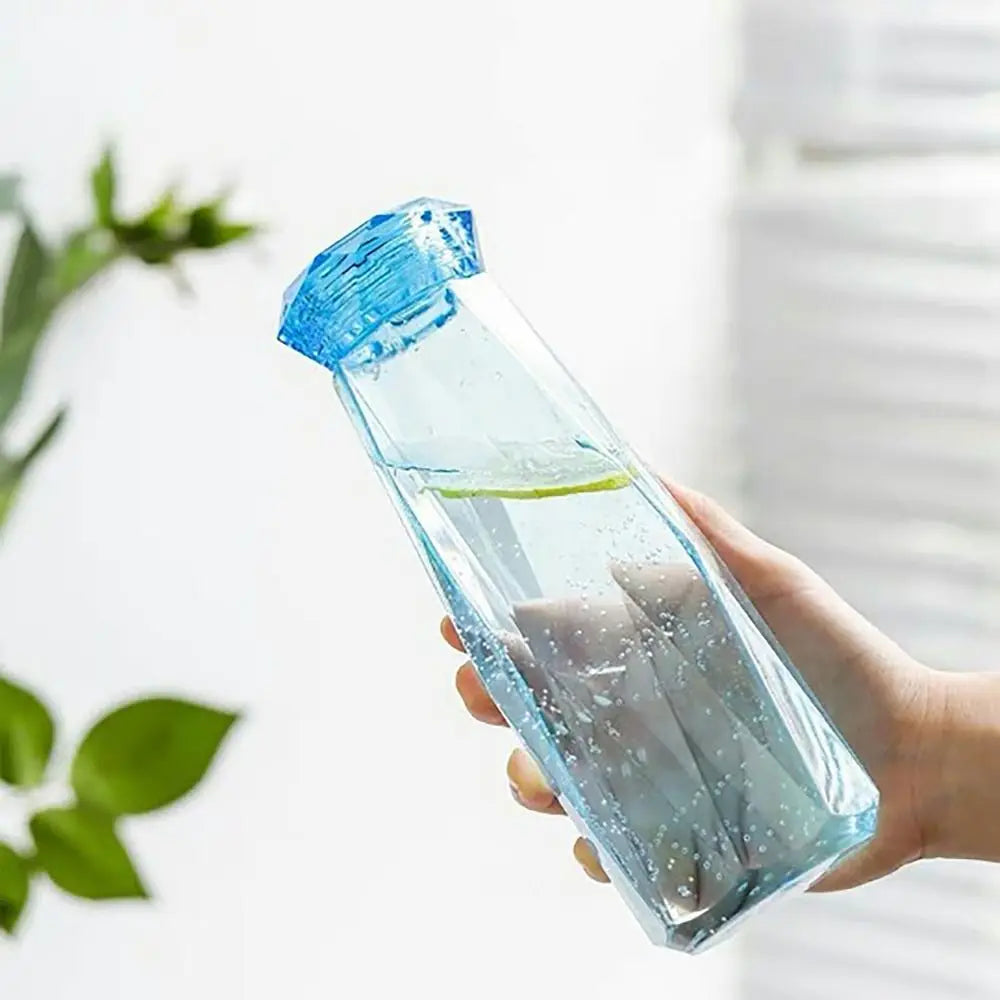 Hand holding clear blue portable sport drink bottle filled with water and lemon slice