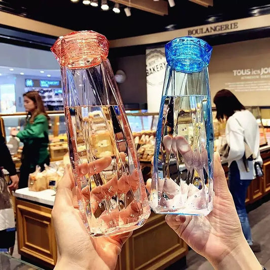 Two hands holding portable sport drink bottle with red and blue caps in a bakery store