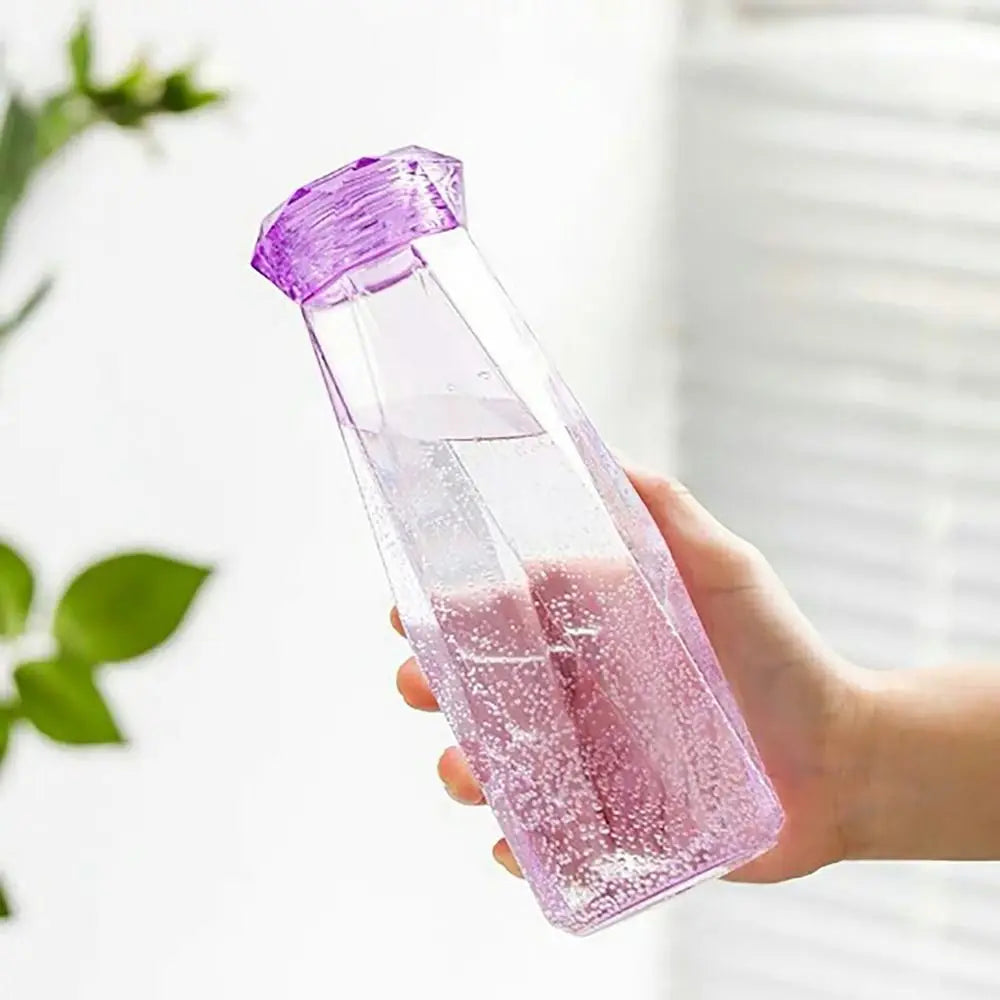 Hand holding a transparent purple portable sport drink bottle filled with water