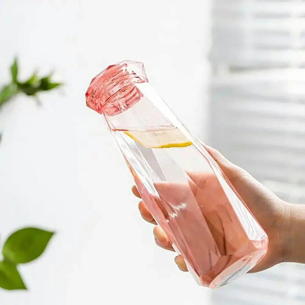 Clear pink portable sport drink bottle with geometric design held in hand with lemon slice inside