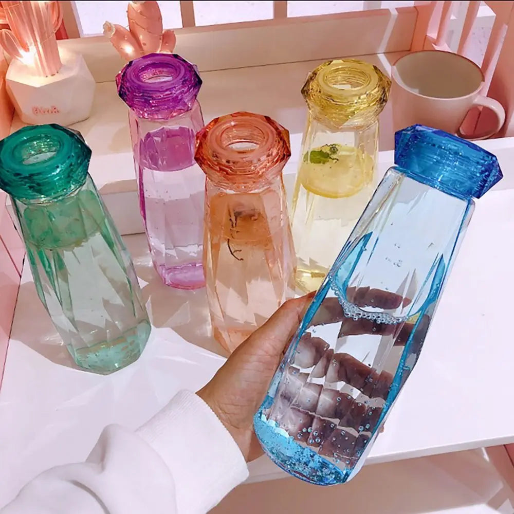 Colorful portable sport drink bottle collection with faceted design, including a blue bottle held in hand