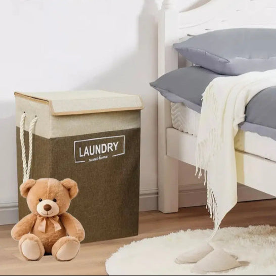 Clarify.pk premium laundry basket with lid in brown and beige placed next to a bed with a teddy bear