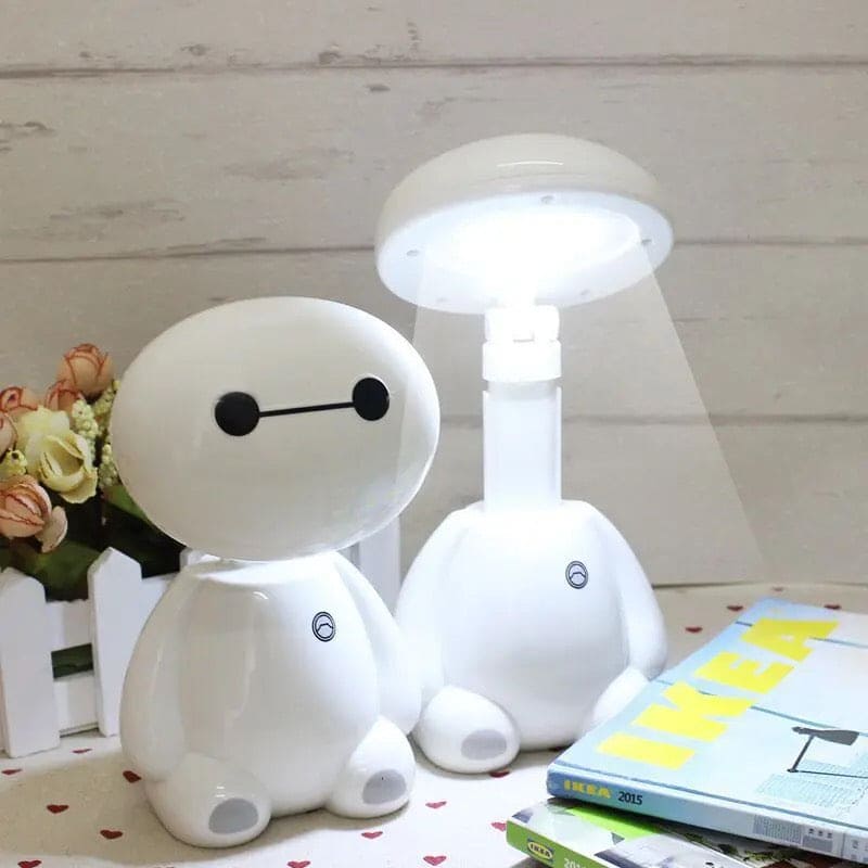 Rechargeable study lamp with eye protection designed as a cute white robot sitting on a desk with book stack
