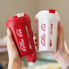 Red and white leakproof thermos coffee mug set with Coca-Cola branding held in hands