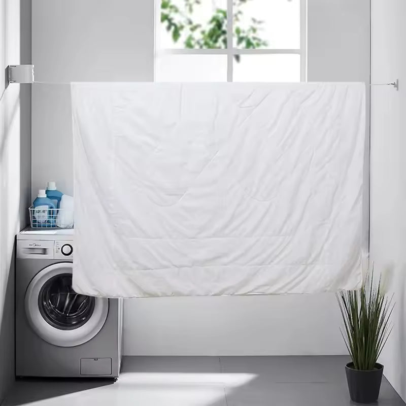 White bedsheet hanging on retractable clothesline in modern laundry room with washing machine