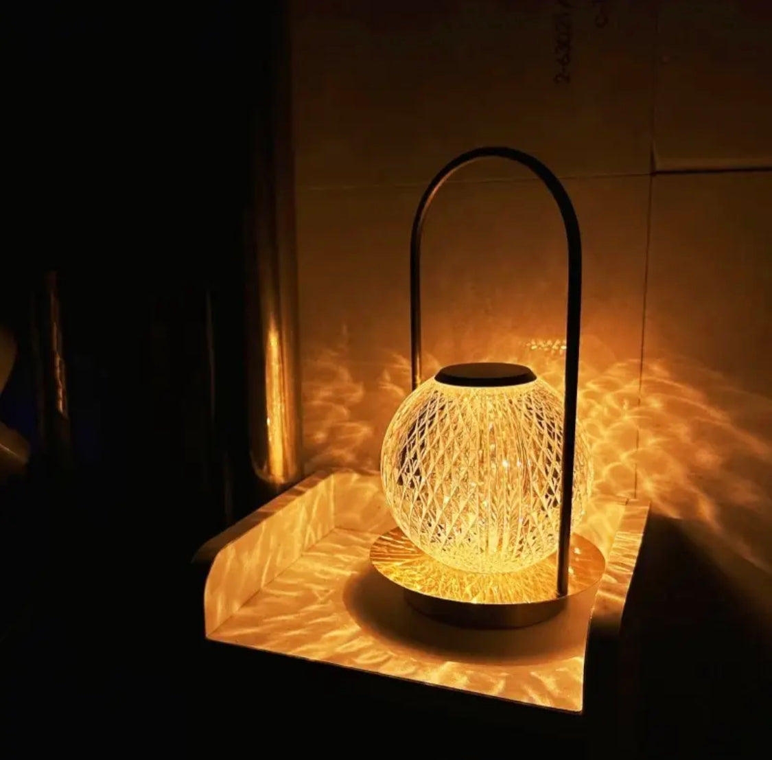 Illuminated retro metal table lamp with a spherical glass shade casting decorative light patterns