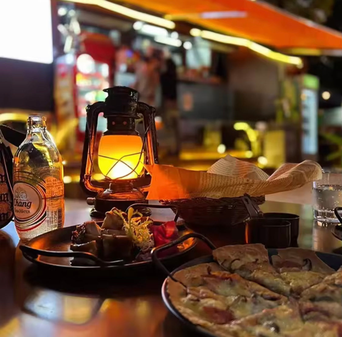 Retro portable lantern rechargeable glowing on a dining table with food and drinks in a cozy outdoor setting