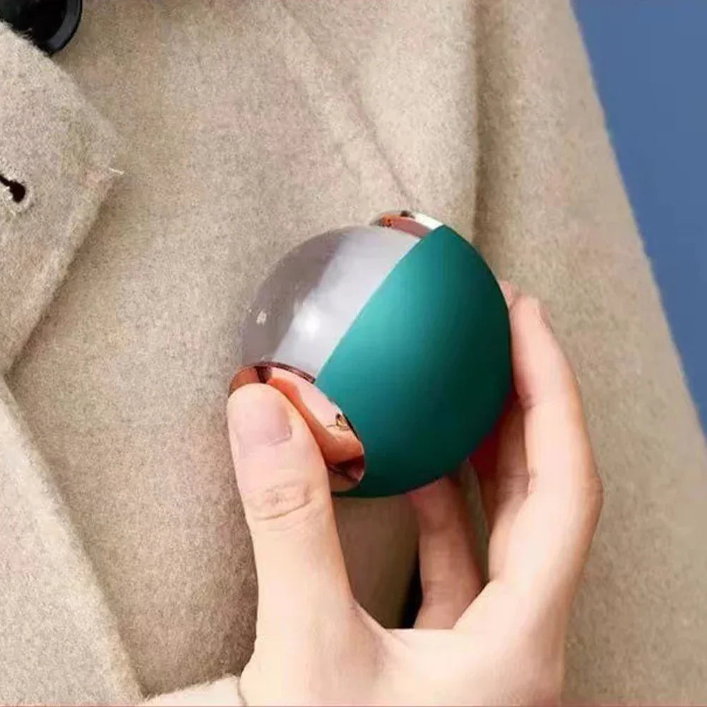 Hand holding a reusable lint roller ball in green and rose gold for removing lint from beige coat