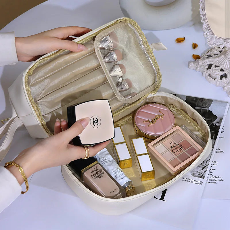 PU leather travel makeup bag open with various cosmetics and brushes inside on white table