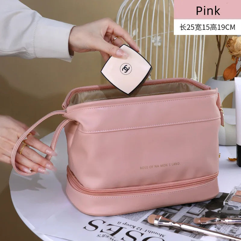 Pink PU leather travel makeup bag with wrist strap on white table being filled with cosmetic compact