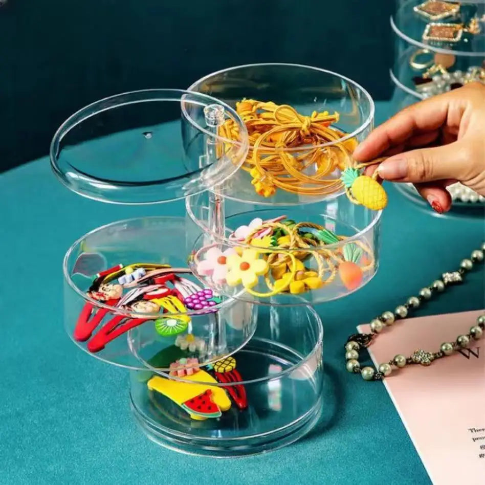 Clarify.pk rotating jewelry storage box with clear compartments holding colorful hair accessories