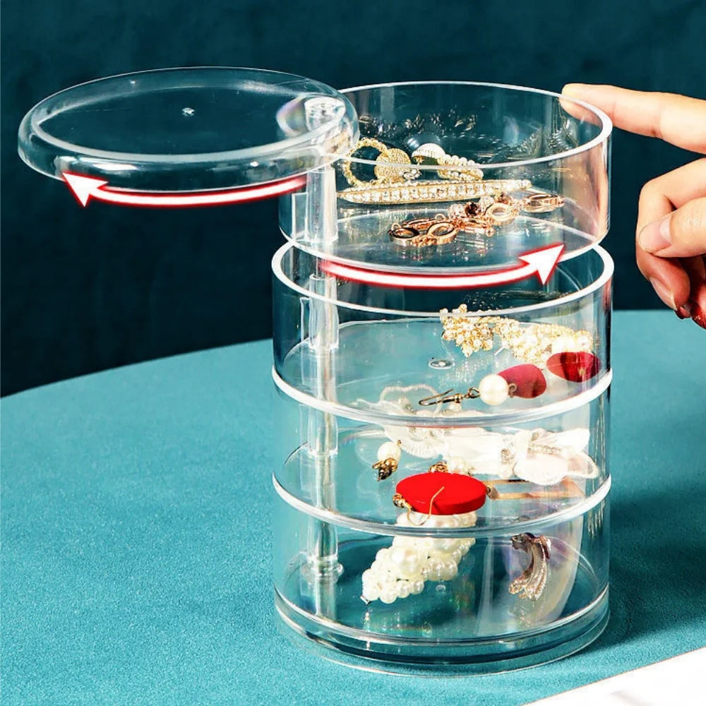 Transparent rotating jewelry storage box by Clarify.pk holding earrings and accessories with a hand opening the top lid