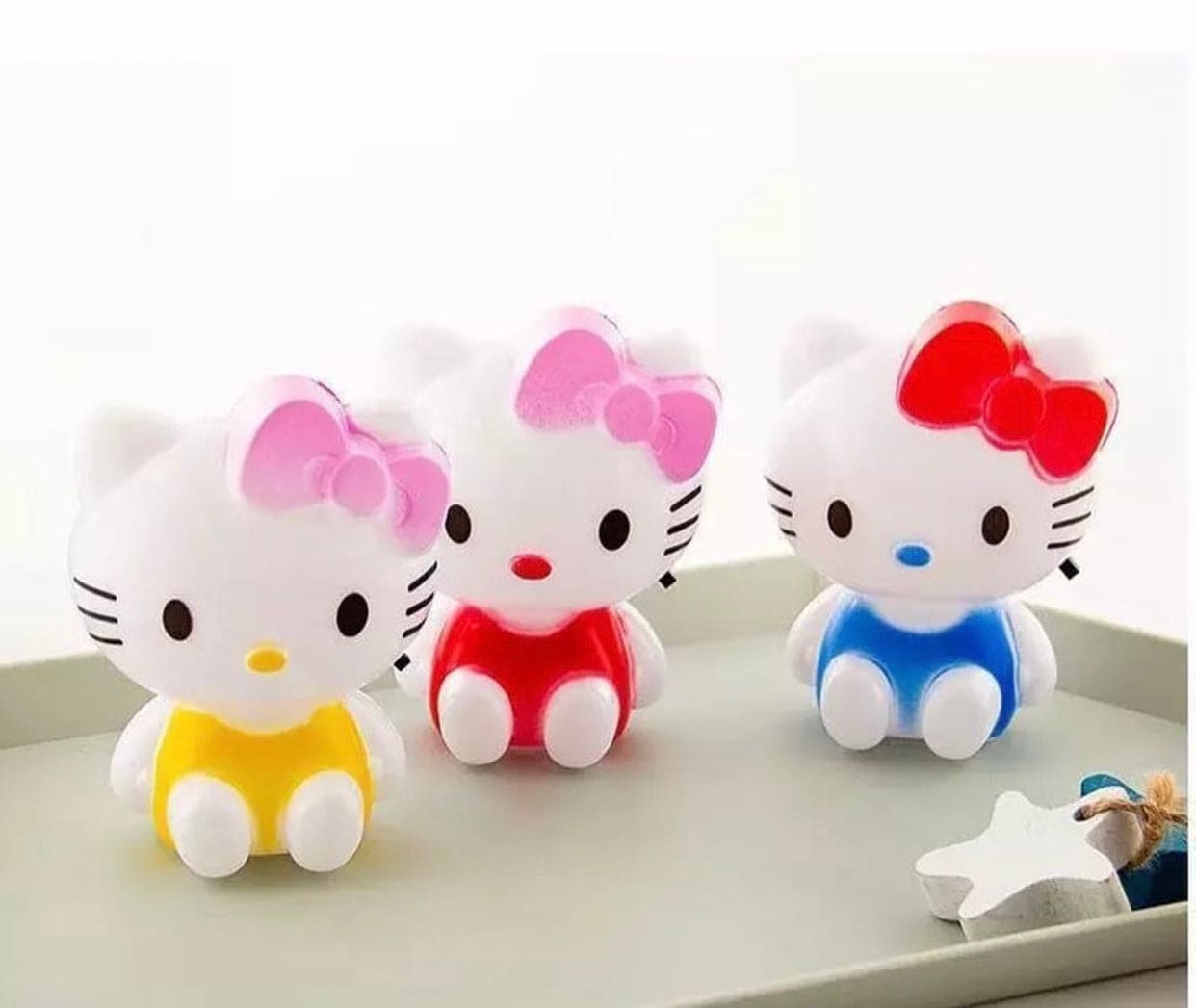 Set of three colorful Hello Kitty night light figures with red, pink, and blue bows sitting on a tray