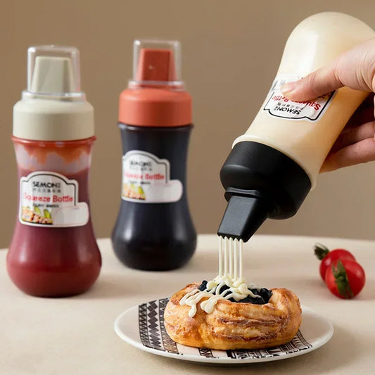 Clarify.pk 350ml sauce squeeze bottle dispensing white sauce over pastry with two other bottles in the background