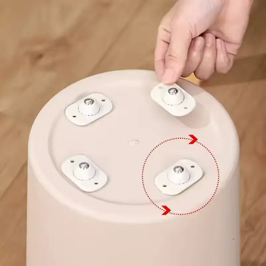 Hand attaching self adhesive furniture wheels to the bottom of a round white plastic stool