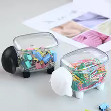 Sheep shaped cotton swab holder made of clear plastic with black and white sheep ears holding colorful paperclips and clips
