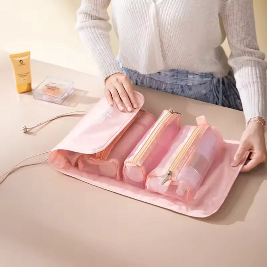 Pink detachable hangable toiletry bag with multiple zippered compartments being opened on a table