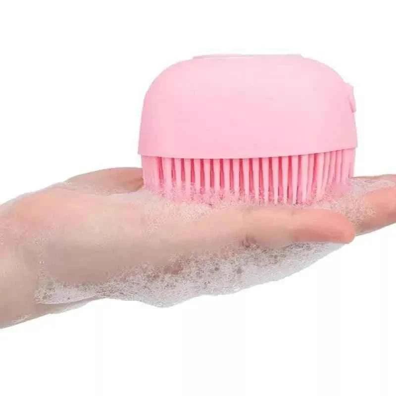 Pink silicone baby bath brush with soft bristles and foam on hand for gentle baby cleaning
