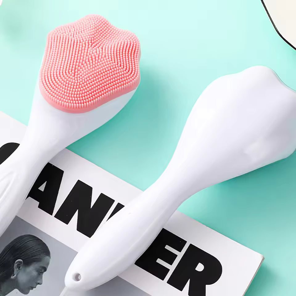 Pink and white silicone face cleaning brush with soft bristles and ergonomic handle on magazine