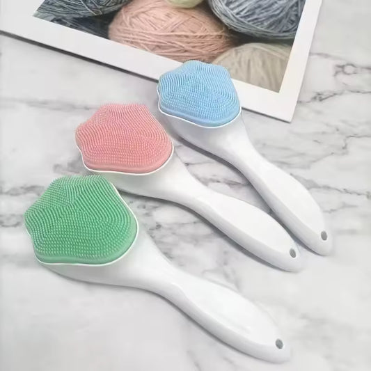 Three silicone facial cleansing brush with white handles in green, pink, and blue colors on a marble surface
