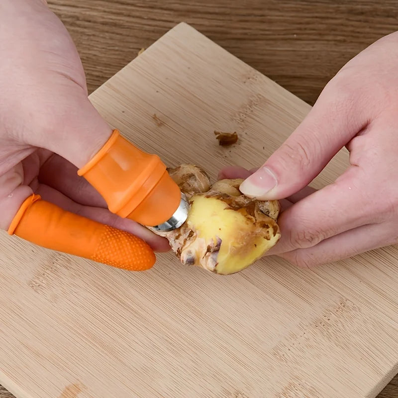Orange silicone finger protector kitchen tool worn on fingers while peeling ginger on wooden cutting board