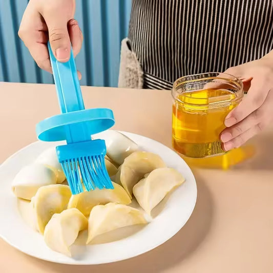 Blue silicone oil brush for baking applying oil on dumplings on white plate