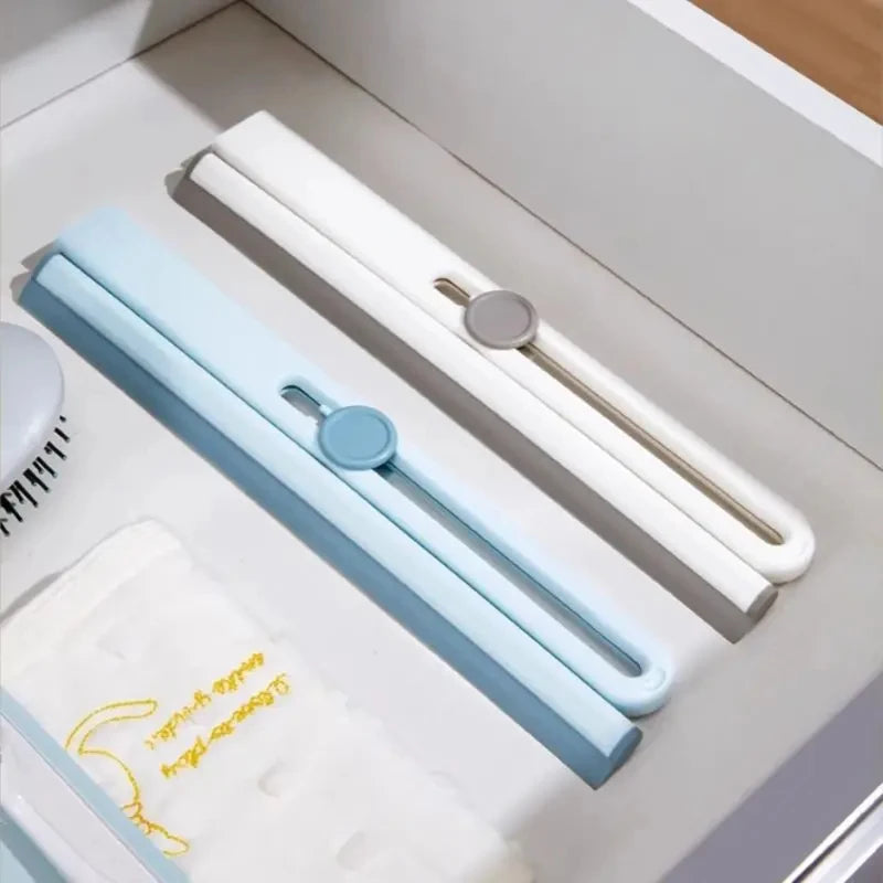 Blue and white silicone shower squeegee set neatly placed in a drawer next to a towel