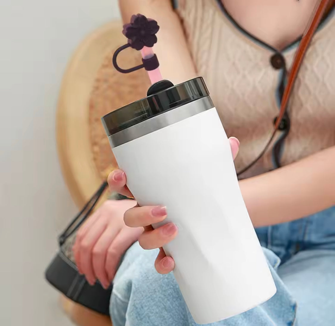 White tumbler with a pink silicone straw topped with a purple flower silicone straw topper