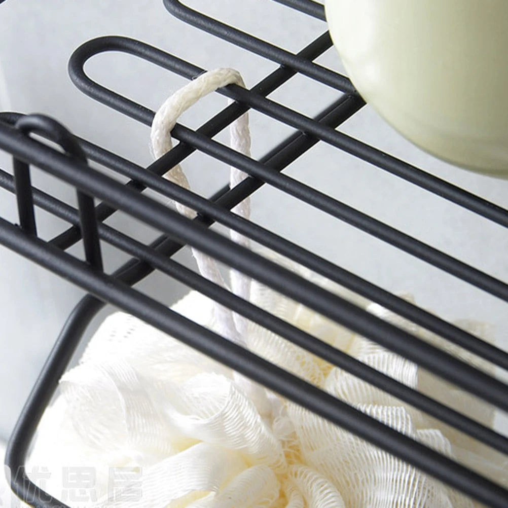 Close-up of black metal sink shelf organizer holding a white scrubbing sponge and kitchen scrubber