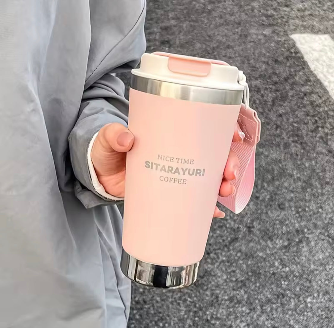 500ml hot and cold water bottle with strap in pink held by a person wearing a gray jacket