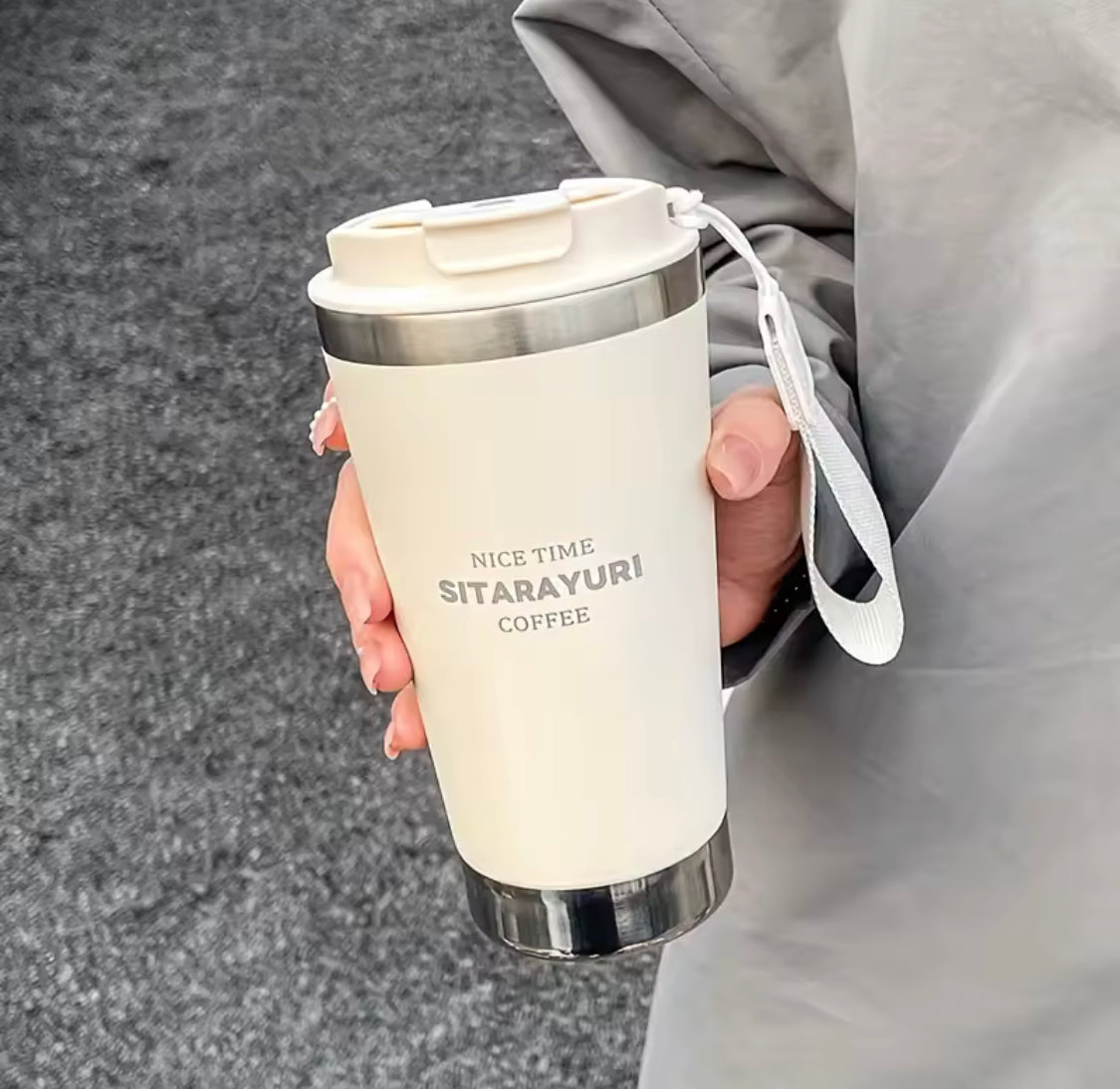 White 500ml hot and cold water bottle with strap held by a person in gray clothing