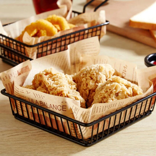 Black metal snack buckets with fried chicken pieces and onion rings on parchment paper