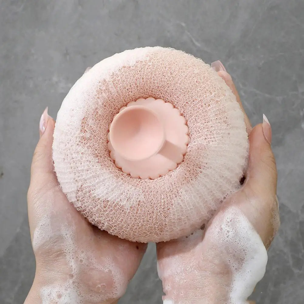 Clarify.pk soft bath brush for exfoliating with a round pink sponge held in hands covered in foam