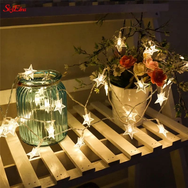 LED star curtain lights for decoration illuminating a glass jar and floral arrangement on a wooden surface