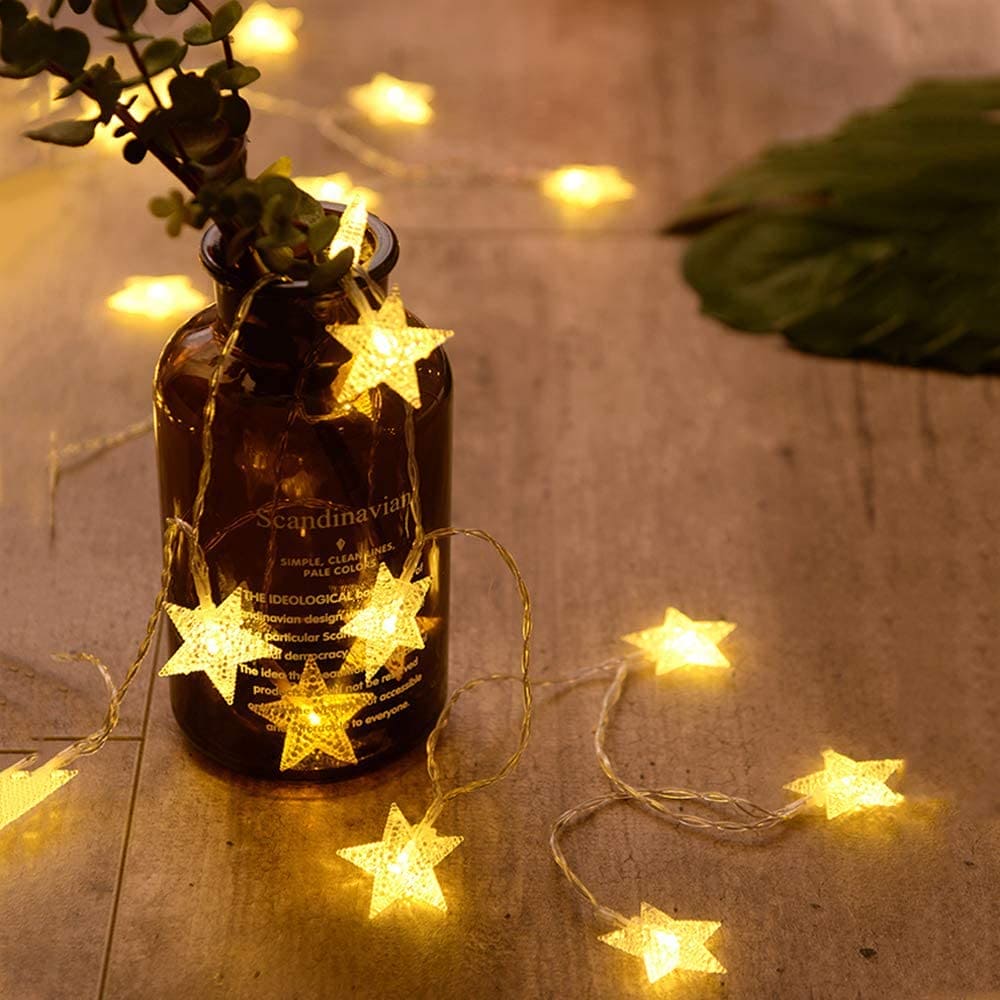 Warm yellow LED star curtain lights for decoration draped around a brown glass bottle on wooden surface