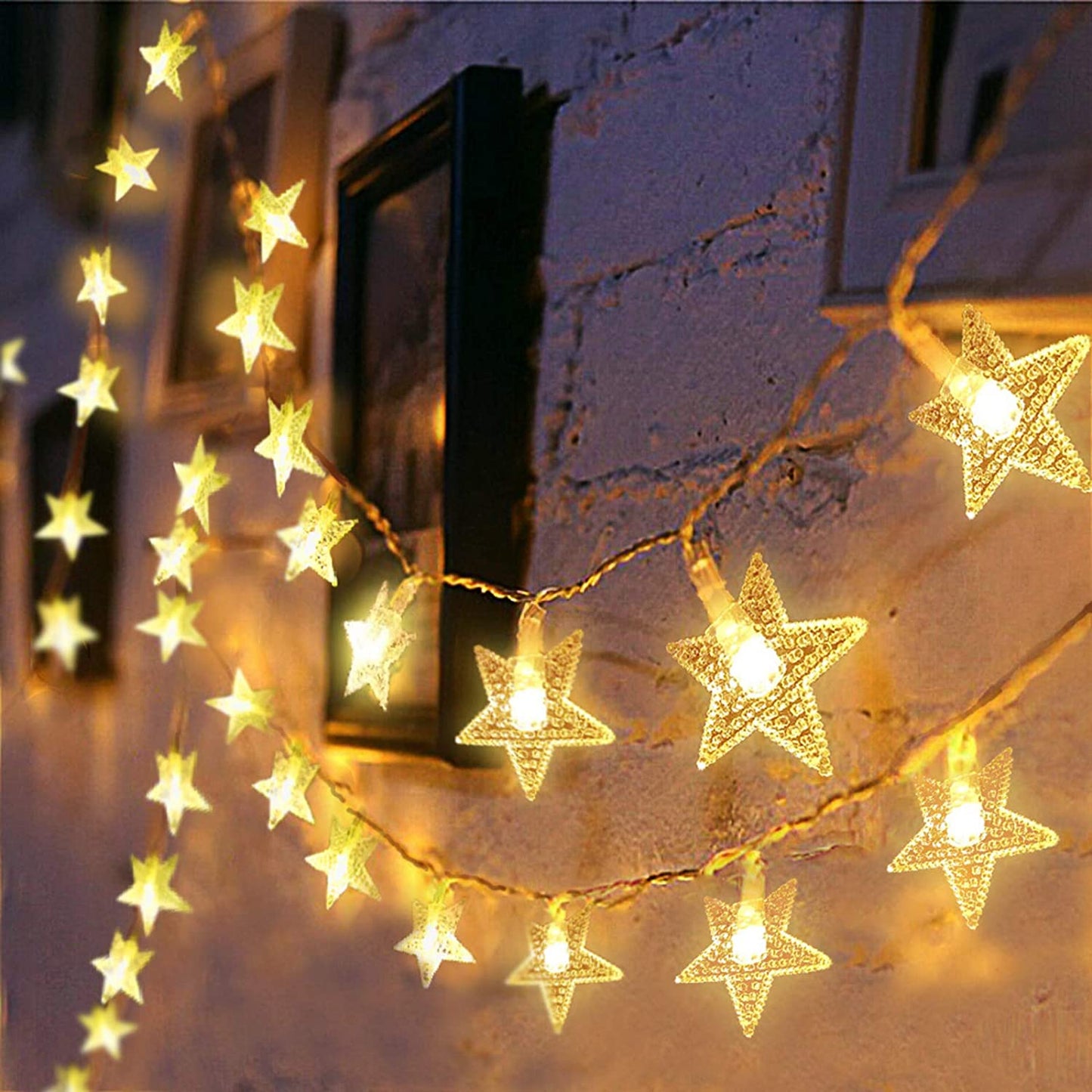 Warm glowing LED star curtain lights for decoration hanging on a textured wall with framed pictures