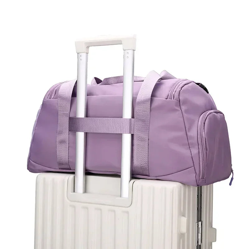 Purple unisex fitness training bag with shoe compartment placed on white suitcase handle