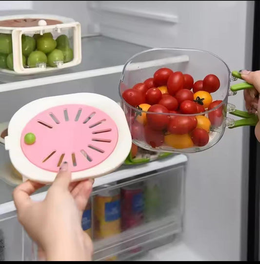 Clear stackable kitchen storage containers with green grapes and cherry tomatoes inside a refrigerator