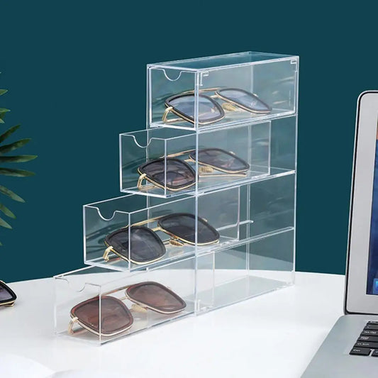 Clear acrylic sunglasses storage box with four compartments holding multiple pairs of sunglasses