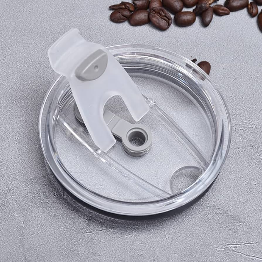 Clear plastic replacement lid for stainless steel coffee tumbler with flip-top opening and coffee beans nearby