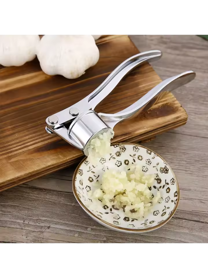 Clarify.pk stainless steel garlic press crushing fresh garlic over a decorative bowl