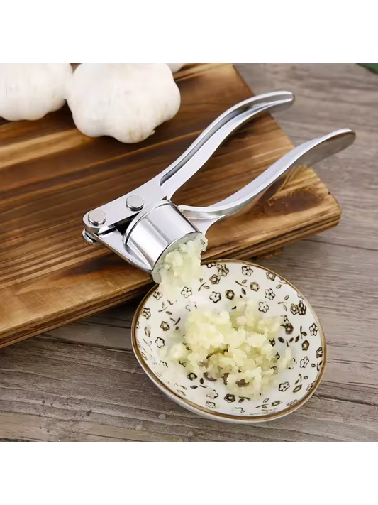 Clarify.pk stainless steel garlic press crushing fresh garlic over a decorative bowl