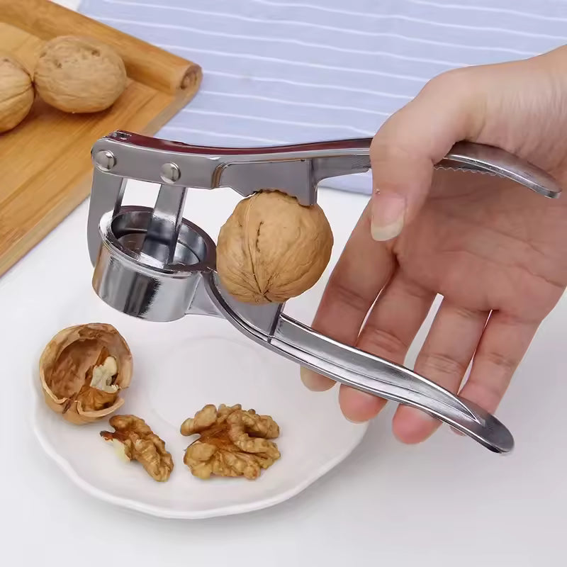 Clarify.pk stainless steel garlic press crushing a walnut held in hand over white plate