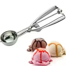 Stainless steel ice cream scoop with ergonomic handle next to three scoops of ice cream with syrup