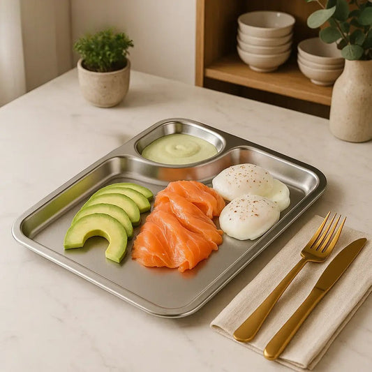 Stainless steel meal tray with avocado slices, smoked salmon, two poached eggs, and sauce in a compartment