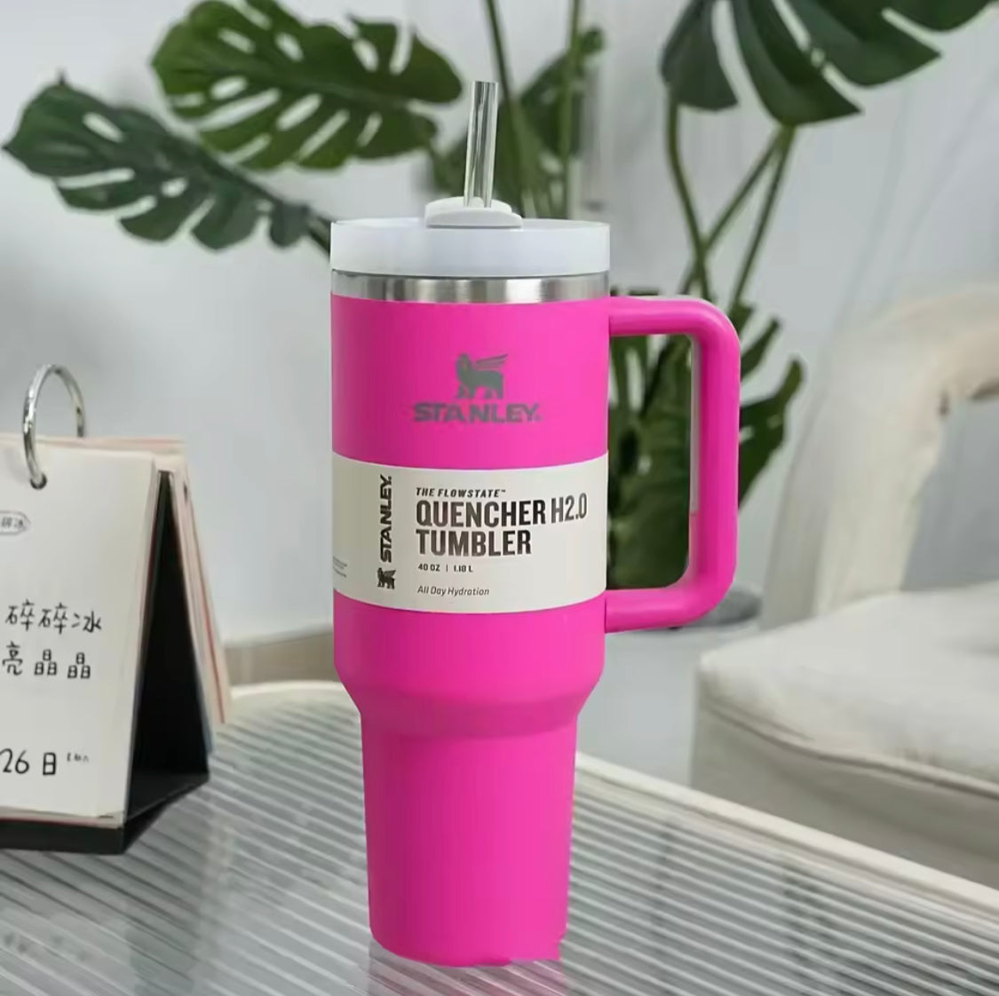 40oz stainless steel tumbler with handle in bright pink with clear straw and white lid on glass table