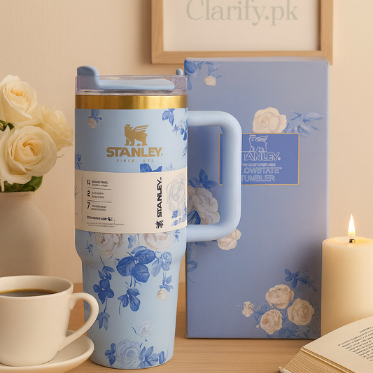 Stanley blue floral tumbler with handle and gold accents next to matching box on wooden surface