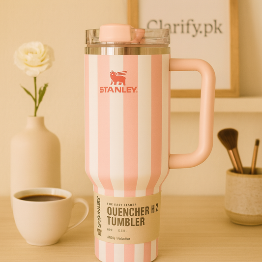 Pink and white striped Stanley quencher tumbler with handle and clear lid on wooden table